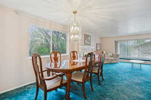 Carpeted dining space featuring a chandelier and baseboards