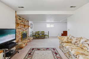 Living room featuring light colored carpet, a fireplace, and a textured ceiling