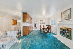 Living area featuring hanging lights, a ceiling fan, dark carpet, and a tile fireplace