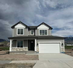 Craftsman inspired home with covered porch, a mountain view, stone siding, driveway, and roof with shingles