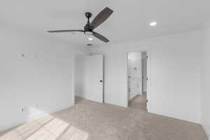 Unfurnished bedroom with connected bathroom, light colored carpet, recessed lighting, and a ceiling fan