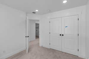 Unfurnished bedroom with light colored carpet, recessed lighting, and a closet