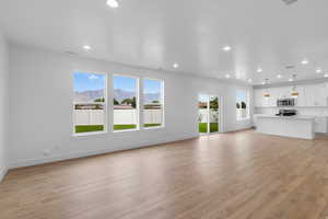 Unfurnished living room with healthy amount of natural light, light wood-type flooring, a mountain view, and recessed lighting