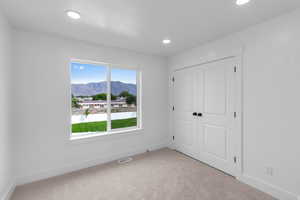 Unfurnished bedroom featuring a mountain view, light carpet, a closet, and recessed lighting