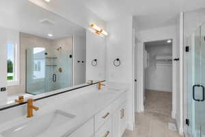 Bathroom featuring a spacious closet, double vanity, a stall shower, a garden tub, and light tile patterned flooring