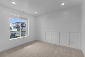Unfurnished room with a decorative wall, wainscoting, light carpet, and recessed lighting