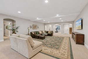 Living room featuring arched walkways, light colored carpet, and recessed lighting