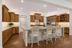 Kitchen featuring hardwood floors and cabinets, double ovens, pot filler, and decorative backsplash