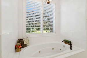 Master bath with two vanities, walk in shower, jetted tub, and marble finishes