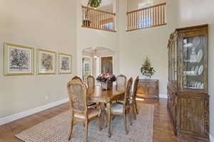 Dining area with arched walkways, dark wood-style floors, and a high ceiling