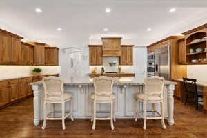 Kitchen featuring hardwood floors and cabinets, double ovens, pot filler, and decorative backsplash