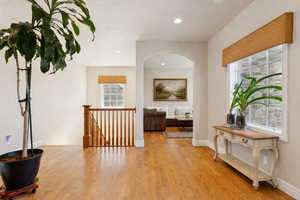 Hall featuring light wood finished floors, an upstairs landing, and recessed lighting