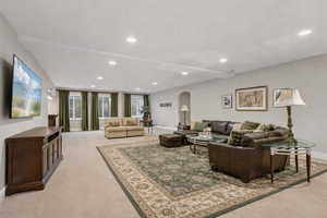 Living area featuring arched walkways, light colored carpet, and recessed lighting