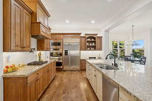 Kitchen featuring hardwood floors and cabinets, double ovens, pot filler, and decorative backsplash
