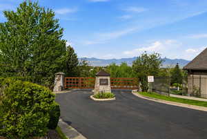 View of asphalt street with a mountain view, a gate, a gated entry, and curbs