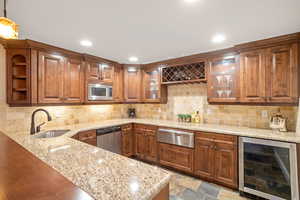 Kitchenette featuring solid wood cabinets, beverage cooler, dishwasher, sink, and warming drawer