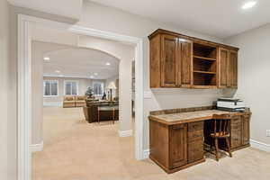 Office / workout area with built in study area, recessed lighting, arched walkways, and light carpet