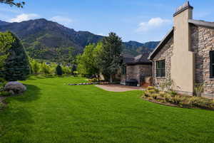 View of green lawn featuring a patio and a mountain view