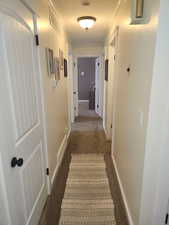 Corridor with dark colored carpet and ornamental molding