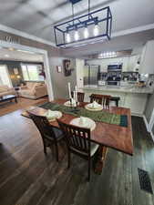 Dining area featuring crown molding and dark wood finished floors