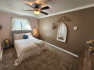 Bedroom with crown molding, a textured ceiling, carpet, and a ceiling fan