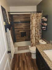 Full bath featuring vanity, dark wood-style floors, a textured ceiling, and shower / bath combination with curtain