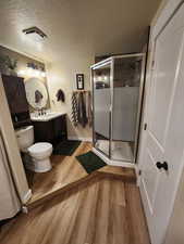 Bathroom with vanity, a stall shower, light wood-style flooring, and a textured ceiling