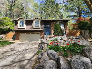 View of front of property with concrete driveway, brick siding, and an attached garage