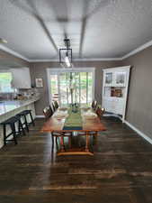 Dining area with dark wood-style floors, a textured ceiling, and ornamental molding
