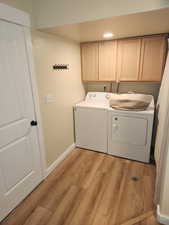 Laundry area with cabinet space, light wood-style flooring, washing machine and dryer, and recessed lighting