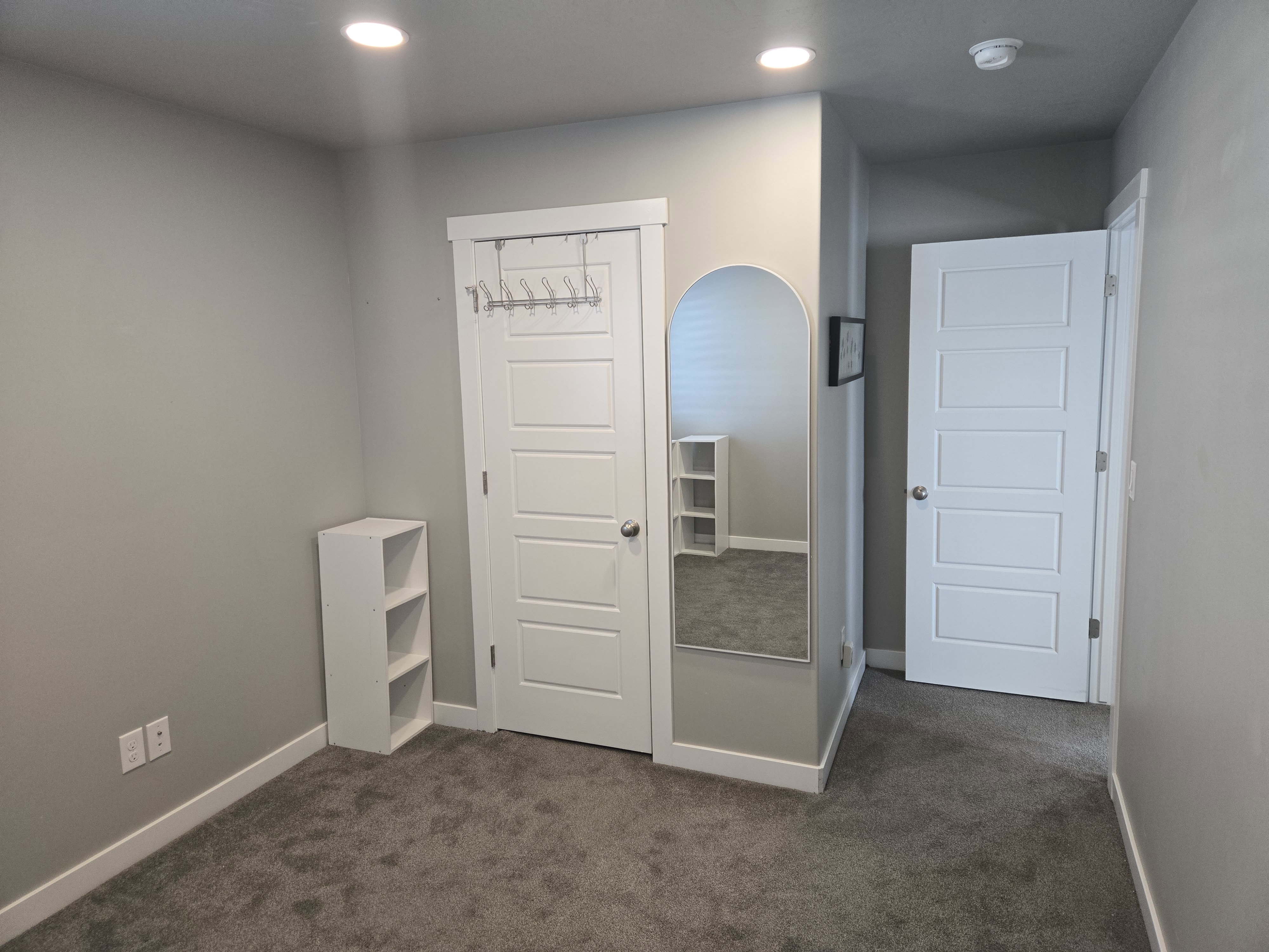 Neutral gray wall tones, recessed ceiling lighting, and gray carpeting