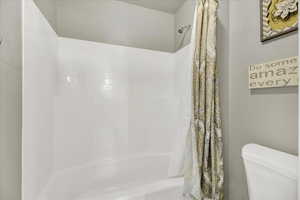 Full bath featuring toilet and shower / tub combo with curtain
