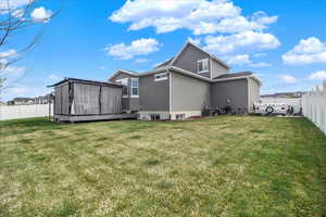 Back of house with a fenced backyard, stucco siding, and a storage unit