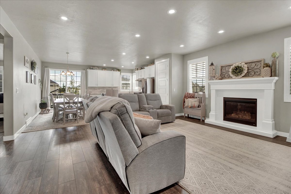 Living room featuring a glass covered fireplace, dark wood finished floors, and suspended lighting