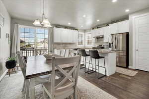 Dining room with dark wood-type flooring and suspended lighting