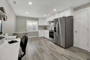 Kitchen featuring stainless steel appliances, white cabinetry, light countertops, light wood finished floors, and recessed lighting