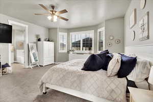 Carpeted bedroom featuring ceiling fan and ensuite bathroom