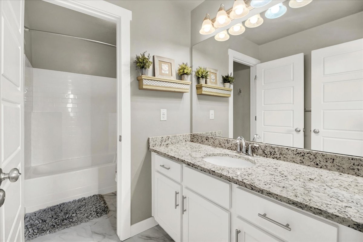 Bathroom with vanity, light marble finish floors, and bathtub / shower combination