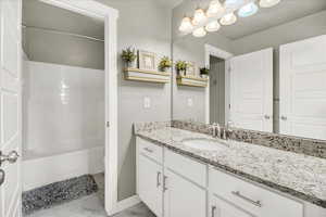 Bathroom with vanity, light marble finish floors, and bathtub / shower combination