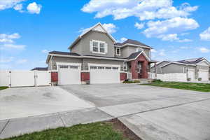 View of front of property featuring a gate, brick siding, stucco siding, driveway, and an attached garage