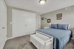 Carpeted bedroom with a closet and baseboards