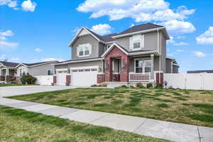 Craftsman-style house with a gate, a porch, brick siding, stucco siding, and a garage