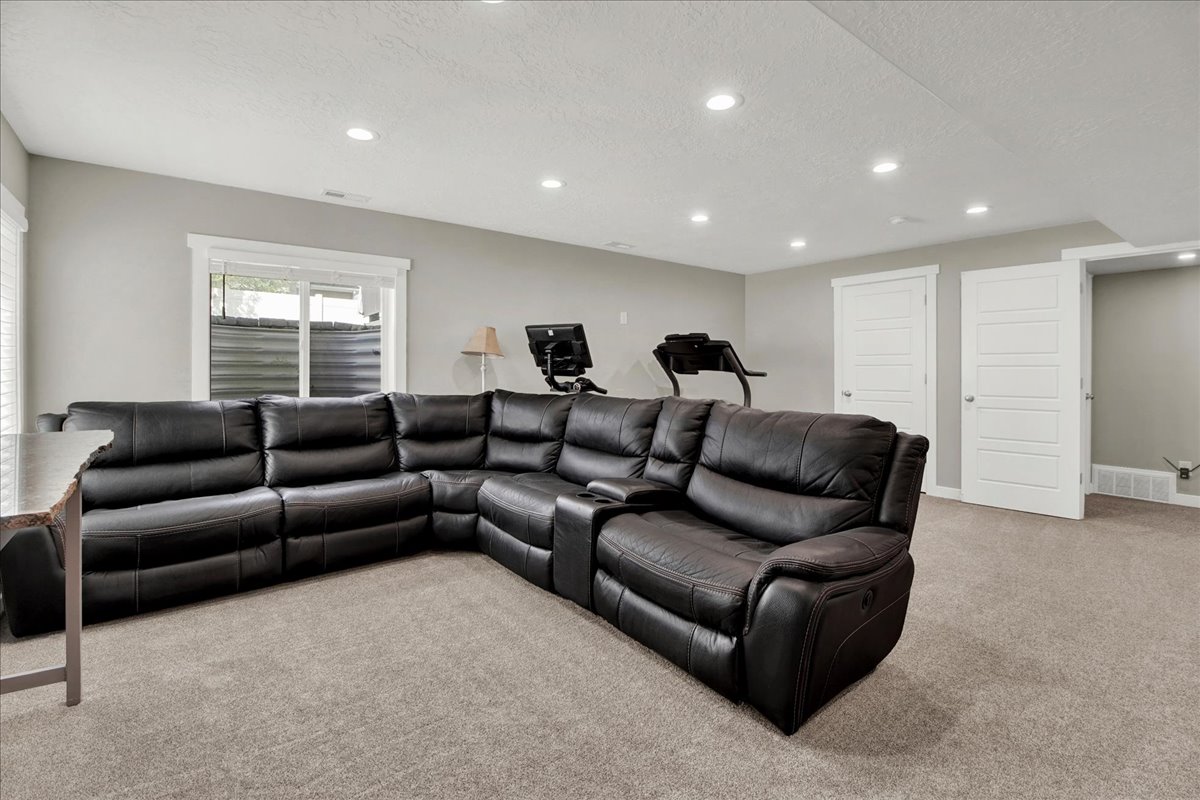 Living area with light carpet, a textured ceiling, and recessed lighting