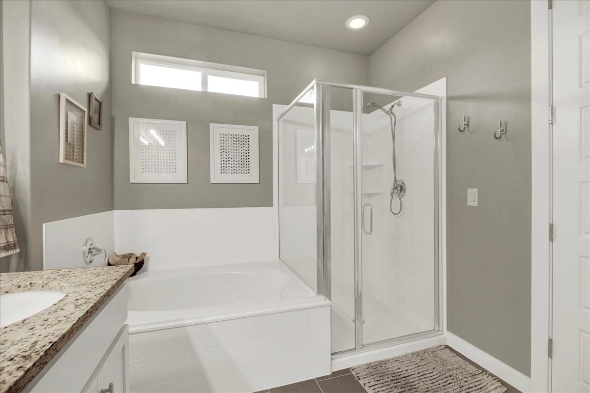 Bathroom with vanity, a garden tub, a stall shower, and dark tile patterned floors
