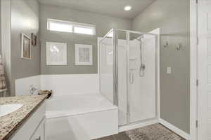 Bathroom with vanity, a garden tub, a stall shower, and dark tile patterned floors