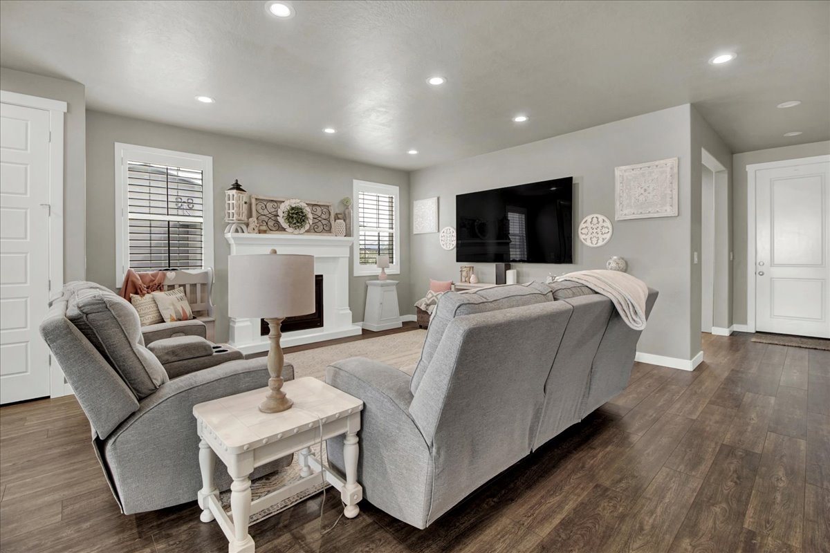 Living area featuring dark wood-style flooring, recessed lighting, and a fireplace with raised hearth
