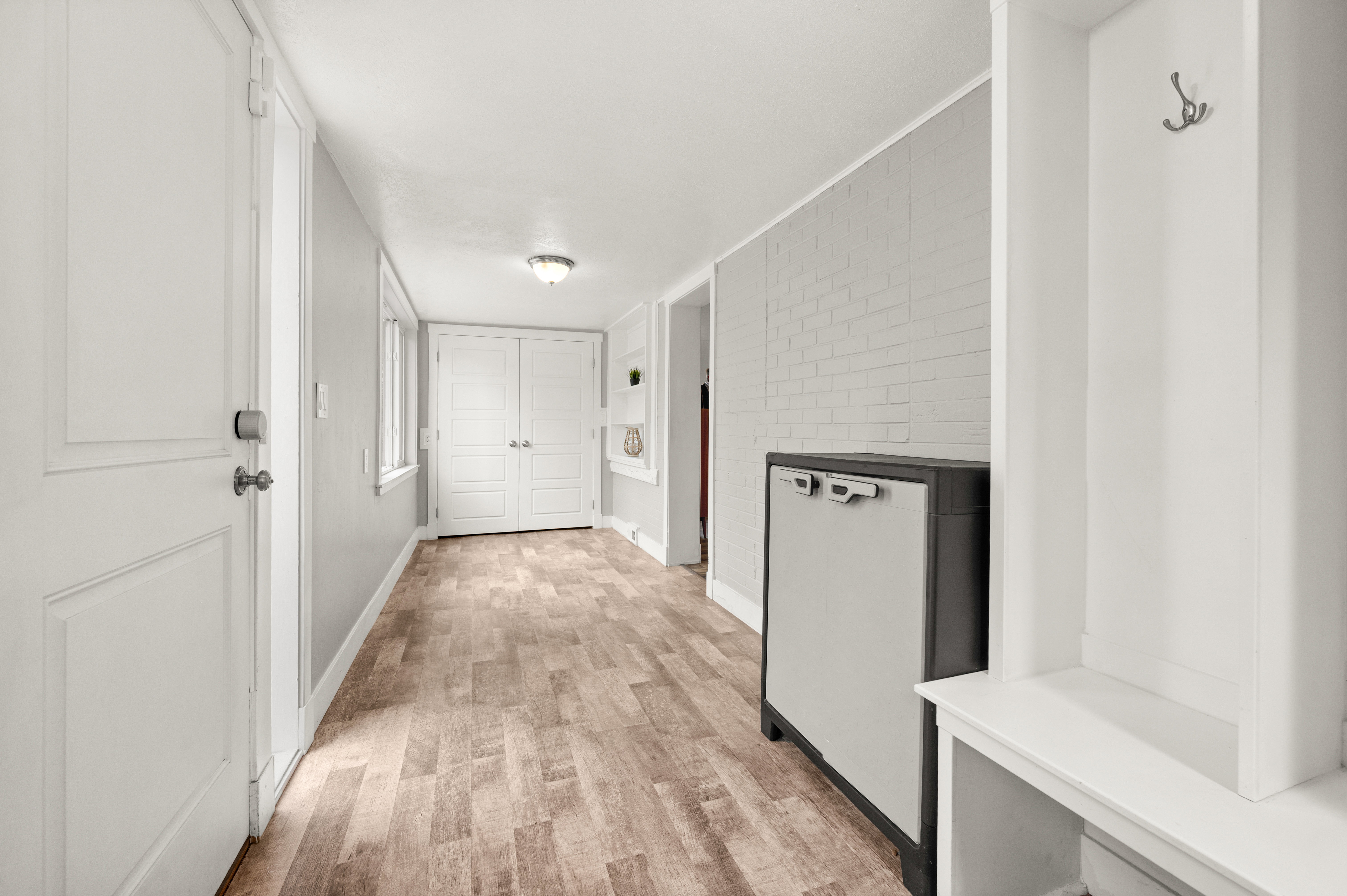 Mudroom featuring light wood-style floors and brick wall