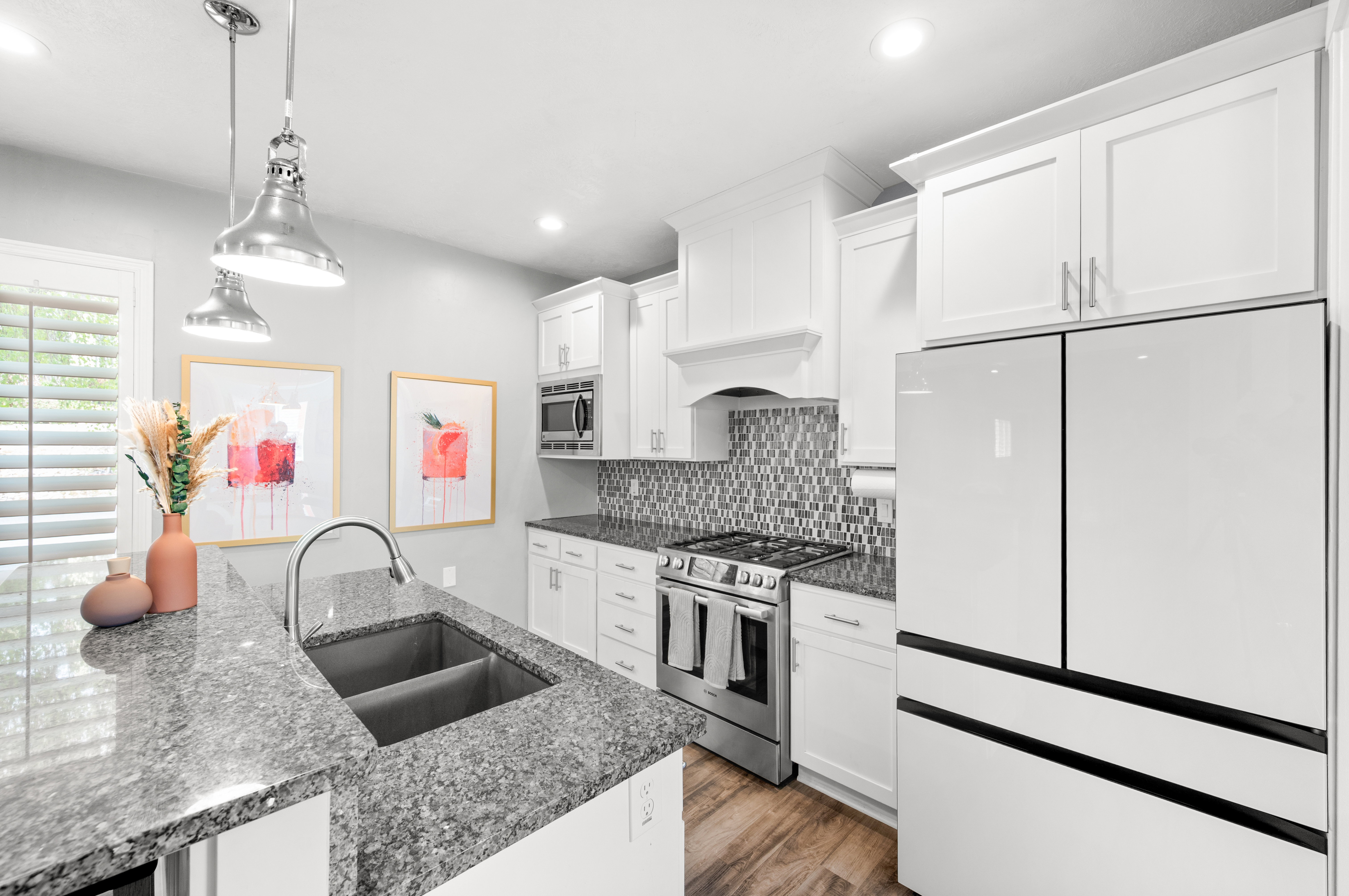 Kitchen featuring white cabinetry, stainless steel appliances, backsplash, and decorative light fixtures