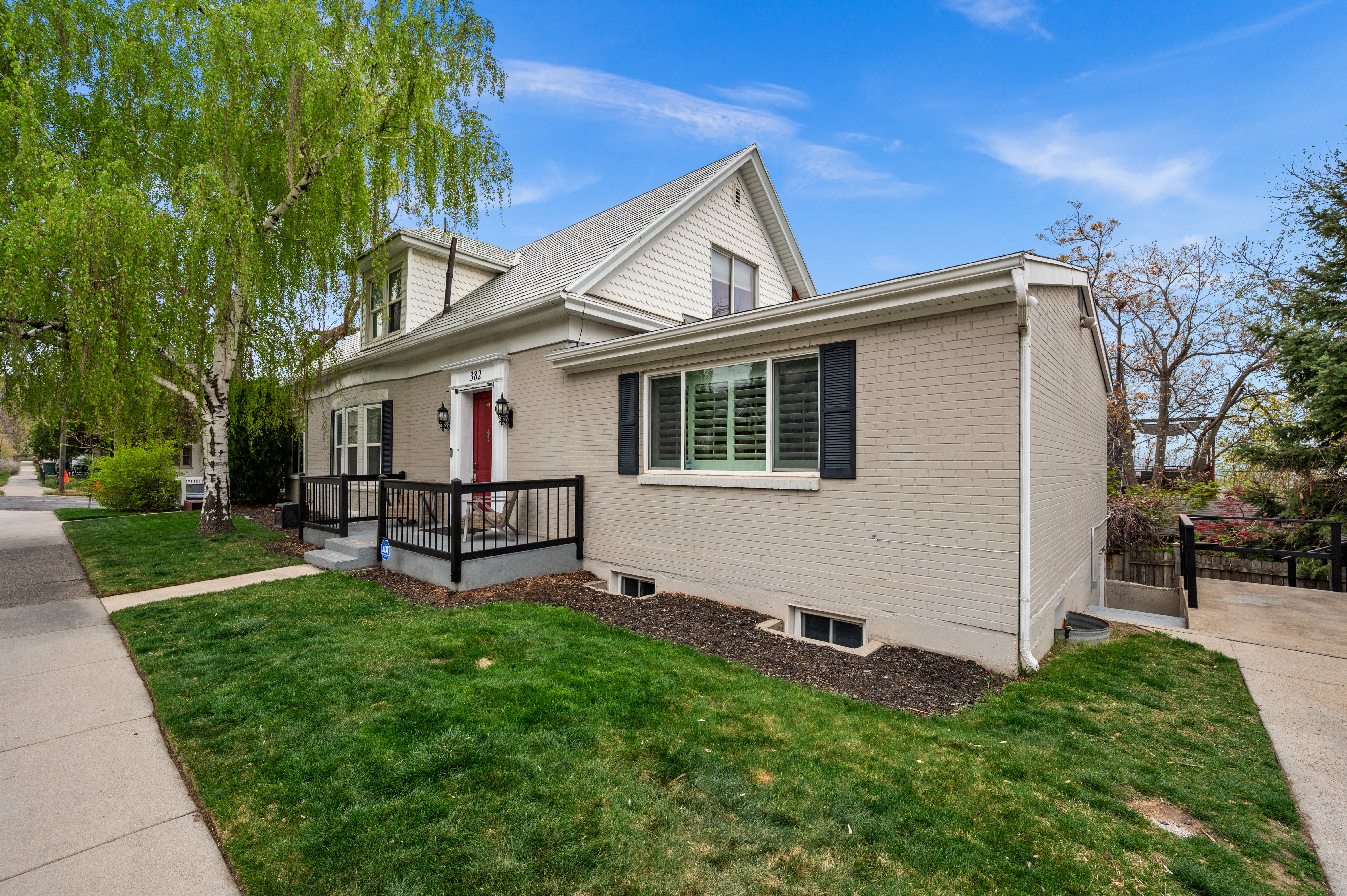 View of front facade with a front yard, brick siding, and a deck
