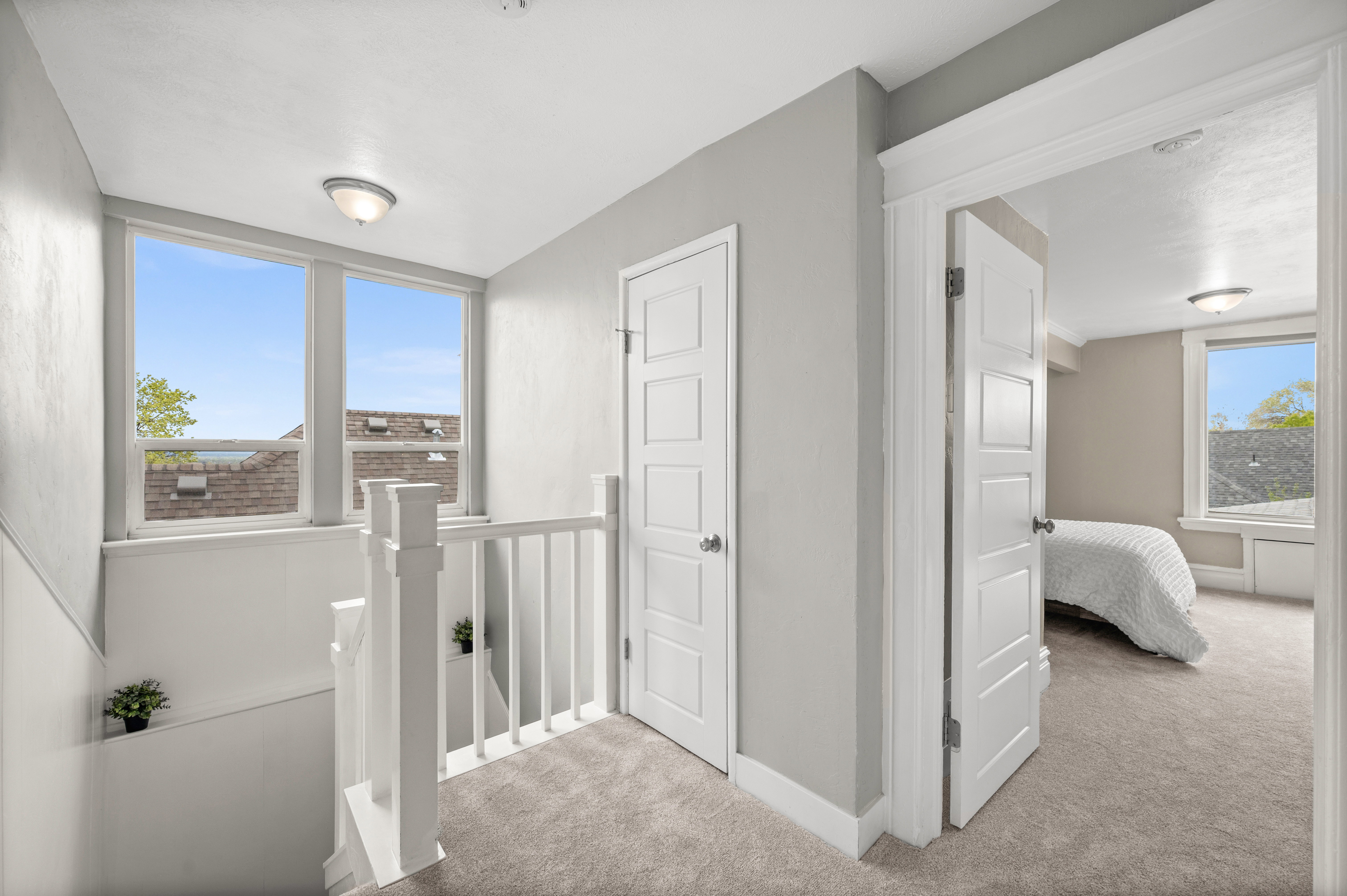 Hall with light colored carpet, an upstairs landing, and plenty of natural light